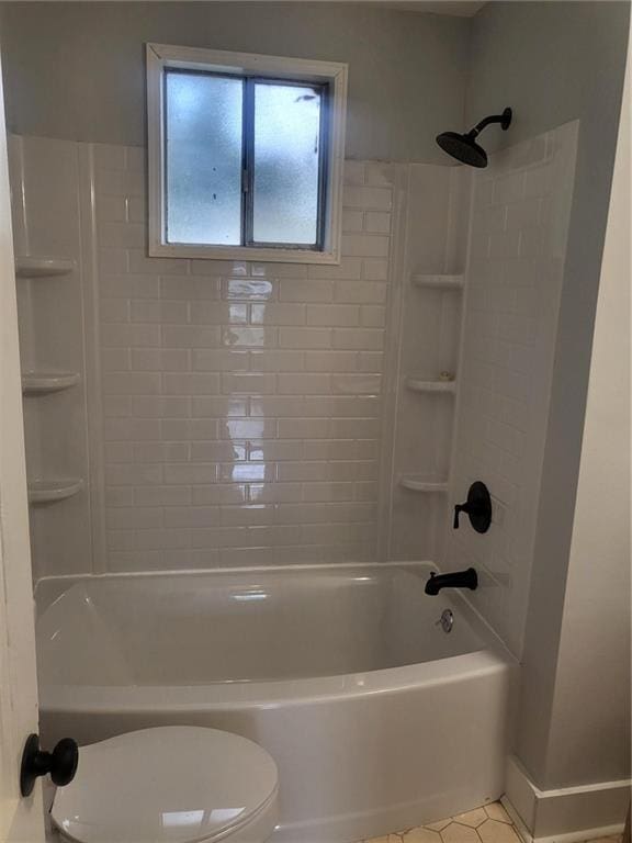 bathroom featuring tiled shower / bath combo, tile patterned floors, and toilet