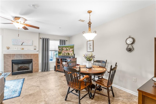 dining room featuring a tiled fireplace and ceiling fan