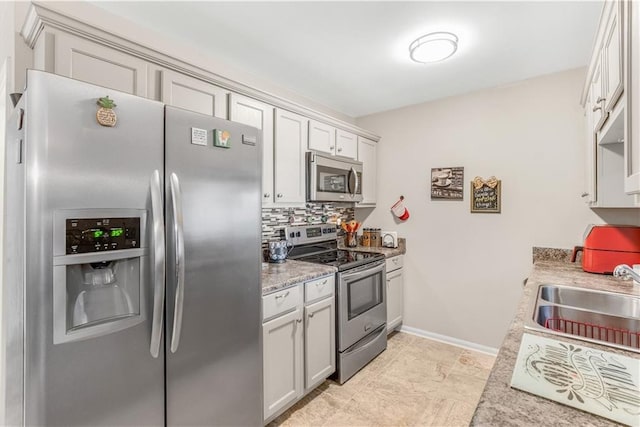 kitchen featuring light stone counters, stainless steel appliances, backsplash, and sink