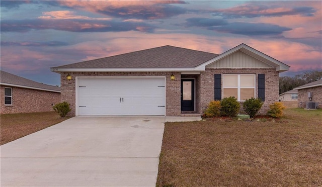 ranch-style home featuring a garage, a yard, and central air condition unit