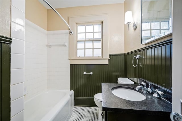 full bathroom featuring wooden walls, vanity, toilet, and tiled shower / bath