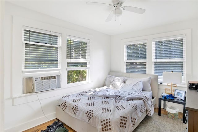 bedroom with cooling unit, ceiling fan, and light hardwood / wood-style flooring