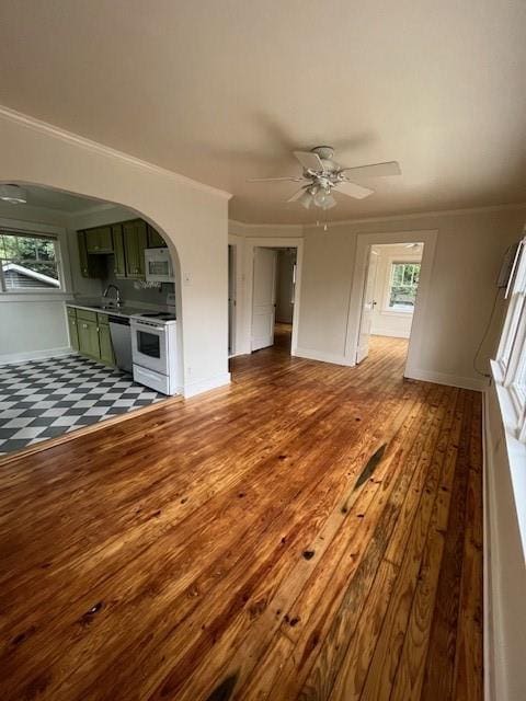 unfurnished living room with hardwood / wood-style floors, crown molding, a wealth of natural light, and ceiling fan