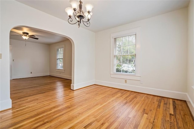 spare room featuring ceiling fan with notable chandelier and light hardwood / wood-style flooring