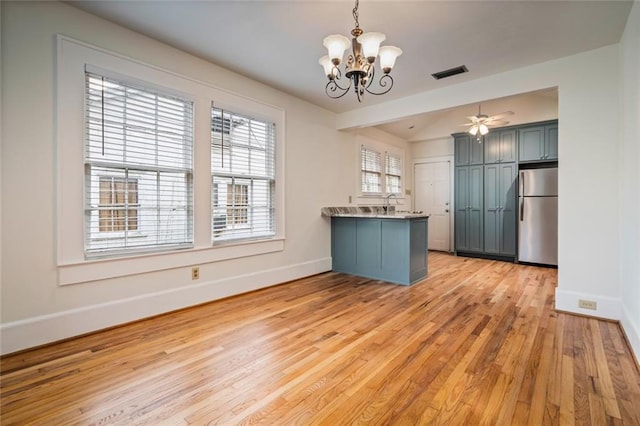 kitchen featuring sink, light hardwood / wood-style flooring, stainless steel refrigerator, kitchen peninsula, and pendant lighting