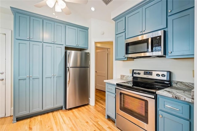 kitchen featuring light stone counters, stainless steel appliances, blue cabinets, and light hardwood / wood-style floors