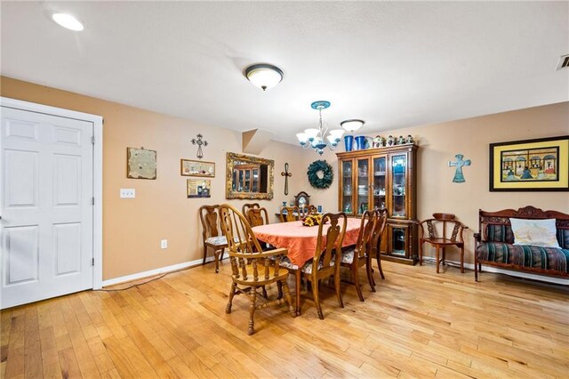 dining space with a notable chandelier and light hardwood / wood-style flooring