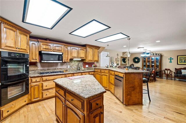 kitchen with a kitchen island, kitchen peninsula, hanging light fixtures, appliances with stainless steel finishes, and a breakfast bar