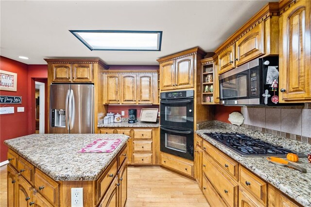 kitchen with light hardwood / wood-style flooring, stainless steel appliances, a center island, and light stone countertops