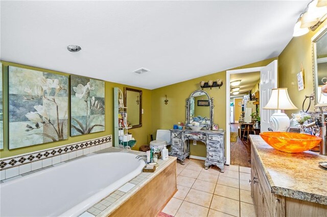 bathroom featuring vanity, toilet, tile patterned flooring, and tiled bath