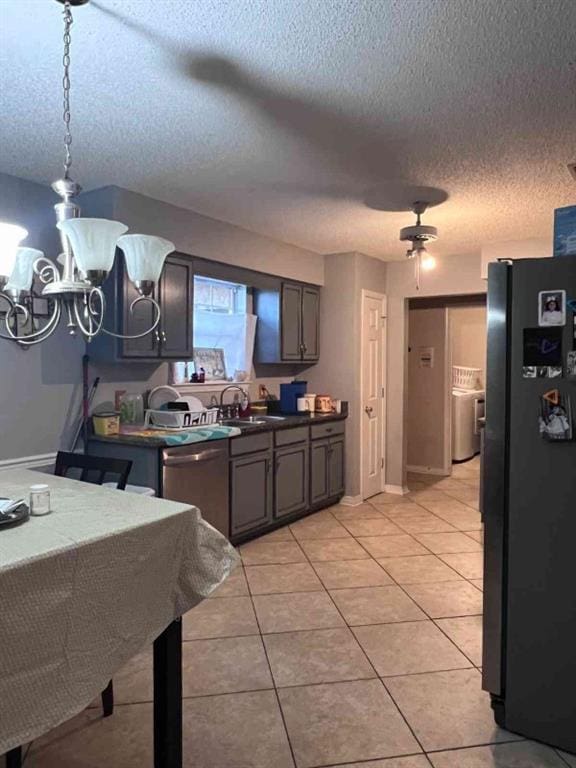 kitchen featuring light tile patterned floors, a textured ceiling, black fridge, and stainless steel dishwasher