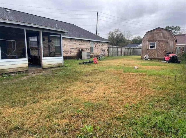 view of yard with an outbuilding, central AC unit, and a sunroom