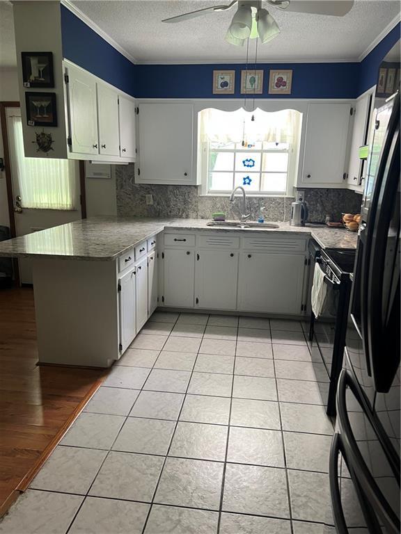 2618 Diberville Dr N, Mobile, AL 36695 - kitchen with a sink, a ceiling fan, a textured ceiling, black appliances, and tasteful backsplash