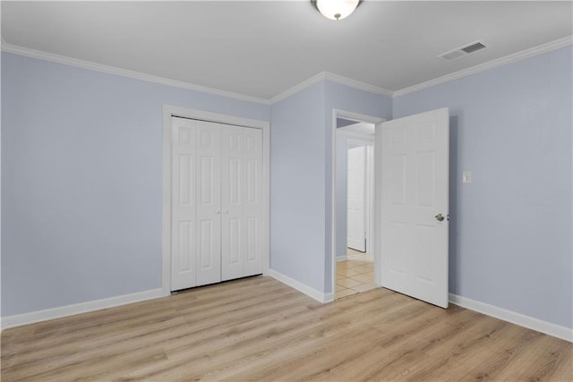 unfurnished bedroom featuring crown molding, light hardwood / wood-style floors, and a closet