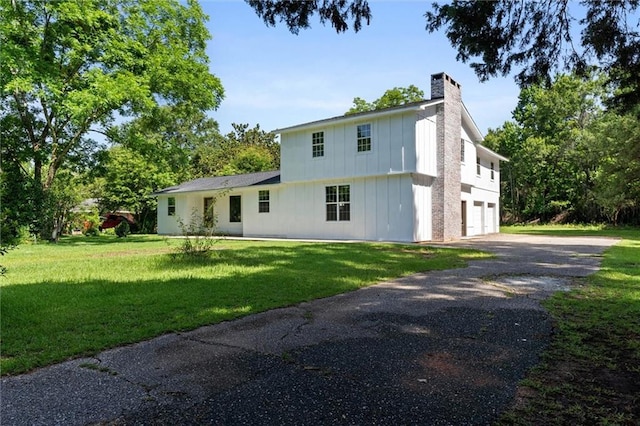 8520 Lebaron Ave W, Citronelle, AL 36522 - view of front facade with board and batten siding, asphalt driveway, a garage, a chimney, and a front yard
