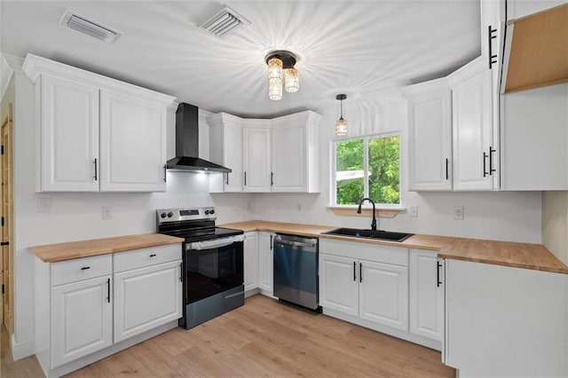 8520 Lebaron Ave W, Citronelle, AL 36522 - kitchen featuring stainless steel appliances, wall chimney range hood, butcher block countertops, and light wood-type flooring