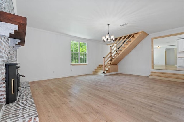 8520 Lebaron Ave W, Citronelle, AL 36522 - unfurnished living room with stairway, light wood-style flooring, a brick fireplace, a chandelier, and crown molding