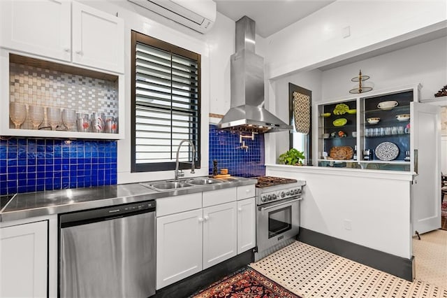 kitchen featuring island exhaust hood, a sink, stainless steel appliances, stainless steel counters, and a wall mounted air conditioner