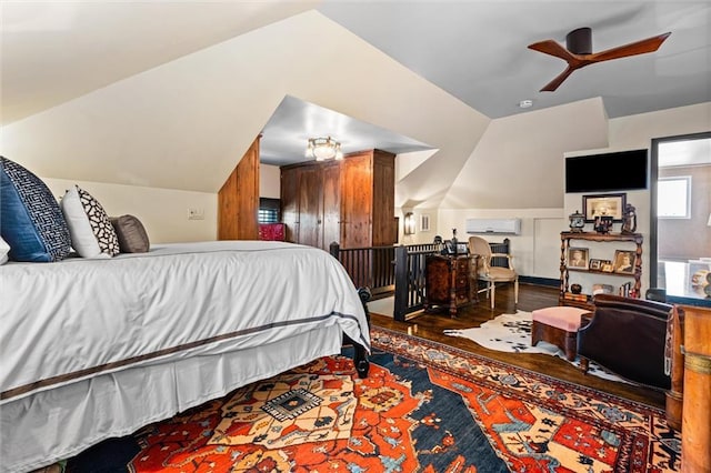 bedroom with an AC wall unit, wood finished floors, and vaulted ceiling