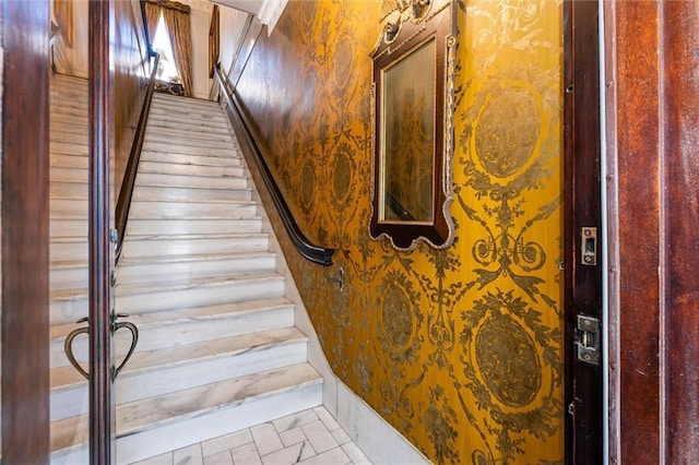 stairway featuring baseboards and wallpapered walls