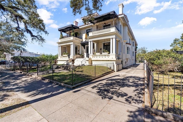 view of front of house featuring a fenced front yard, a front yard, a balcony, and a gate