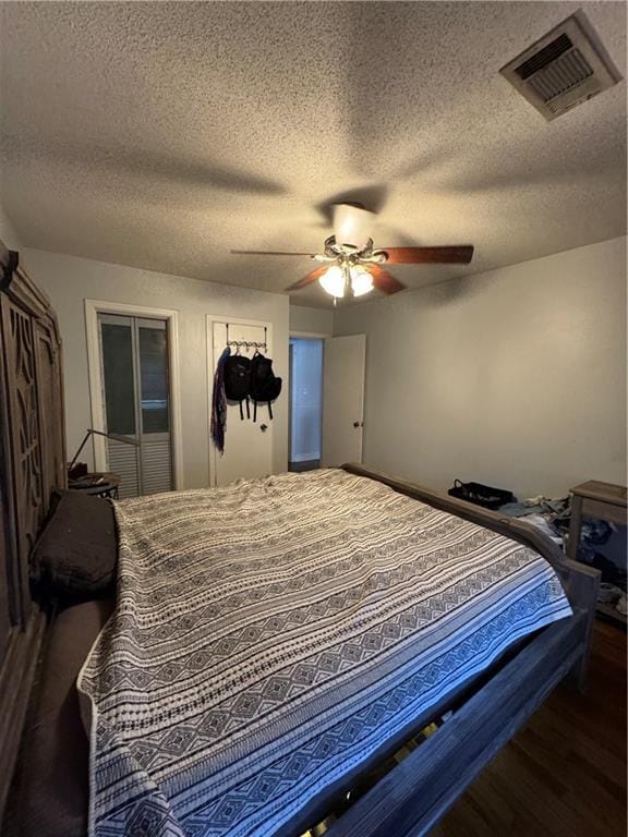 bedroom featuring ceiling fan, dark wood-type flooring, and a textured ceiling