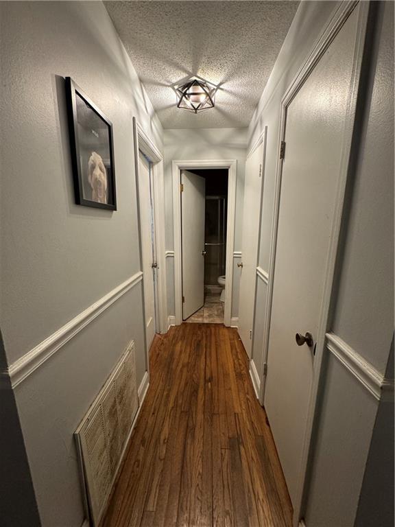 hallway featuring a textured ceiling and dark hardwood / wood-style floors