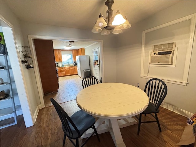 dining space with an AC wall unit, dark hardwood / wood-style floors, and a notable chandelier