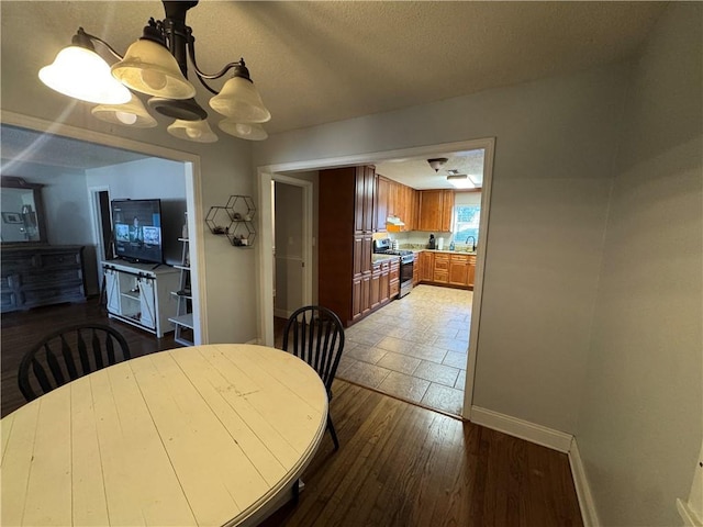 dining area with sink, hardwood / wood-style floors, an inviting chandelier, and a textured ceiling