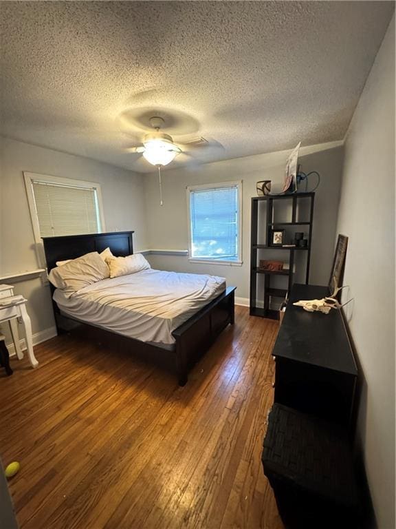 bedroom featuring ceiling fan, dark wood-type flooring, and a textured ceiling