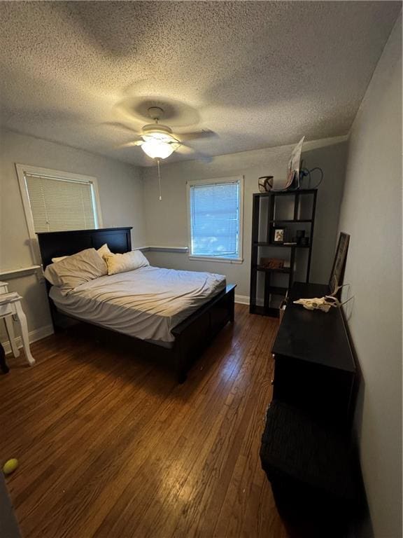 bedroom with ceiling fan, dark hardwood / wood-style floors, and a textured ceiling