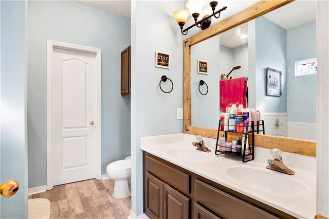 bathroom featuring a notable chandelier, wood-type flooring, vanity, and toilet