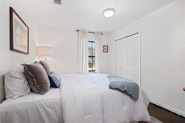4950 Santos Dr E, Mobile, AL 36619 - bedroom featuring wood finished floors, a textured ceiling, a closet, and baseboards