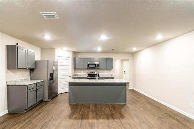 kitchen with dark wood finished floors, stainless steel appliances, visible vents, gray cabinetry, and a sink