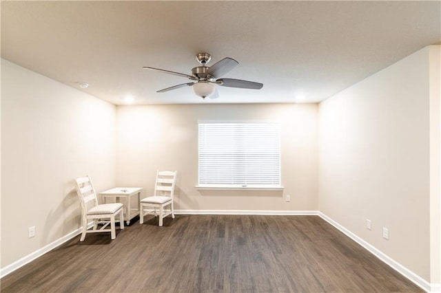 unfurnished room with dark wood finished floors, a ceiling fan, and baseboards