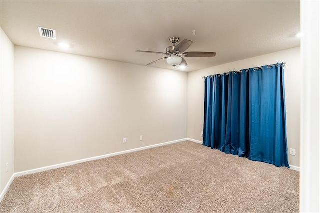 carpeted spare room featuring a ceiling fan, visible vents, and baseboards