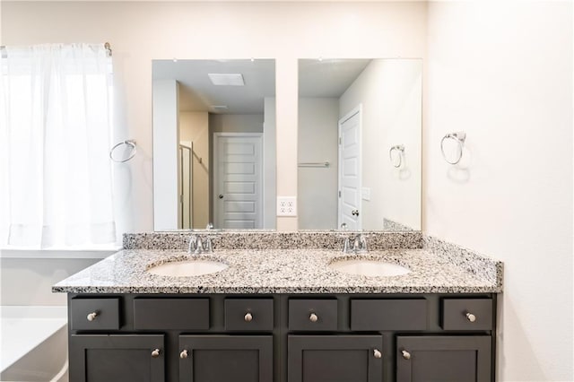 bathroom featuring double vanity, a bathtub, and a sink