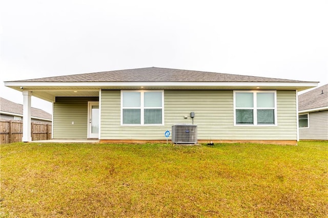 back of house featuring central AC, a lawn, fence, and roof with shingles