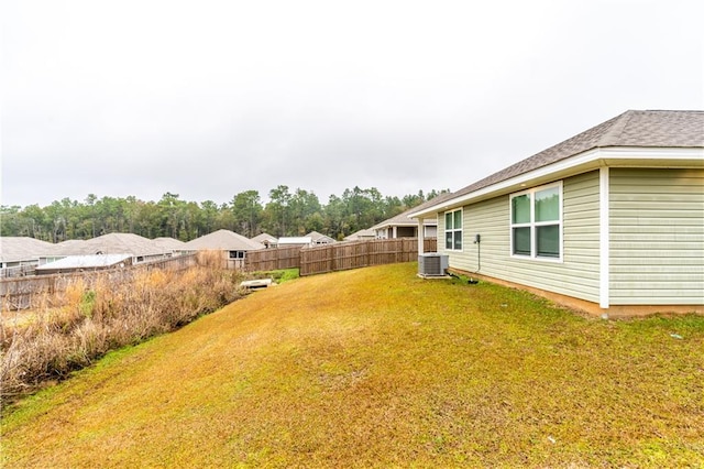 view of yard featuring central AC and fence