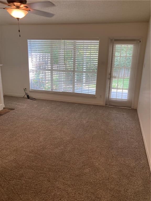 unfurnished room with a textured ceiling, carpet, and ceiling fan