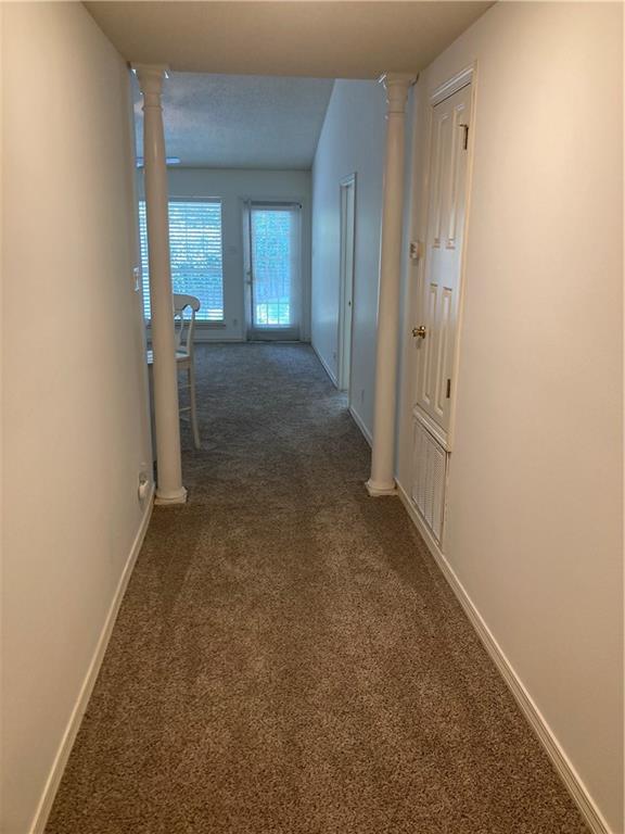 hall with ornate columns and carpet flooring