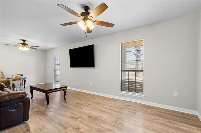 living area with a ceiling fan, light wood-style flooring, and baseboards