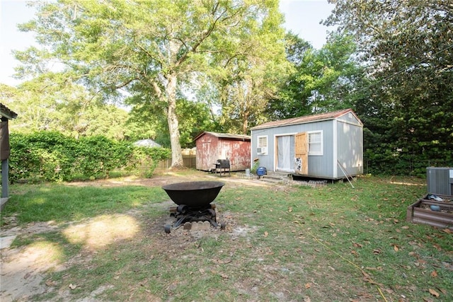 view of yard with central air condition unit, fence, an outbuilding, and a storage unit