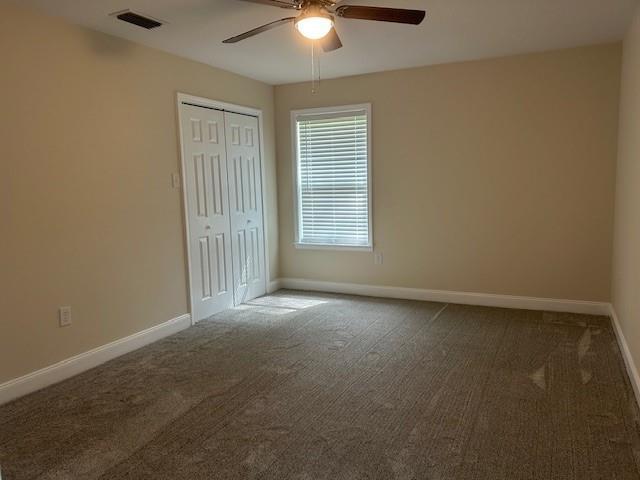 13580 Laco Cooper Rd, Wilmer, AL 36587 - unfurnished bedroom with carpet, baseboards, a closet, and a ceiling fan