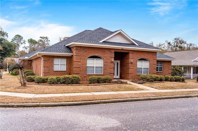 view of front of home with a shingled roof and brick siding