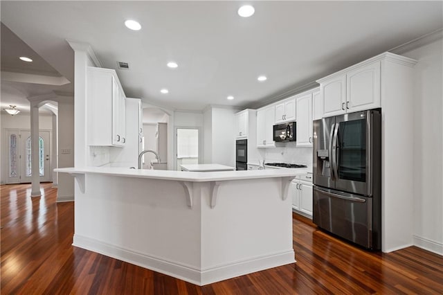 404 Savannah Ln, Foley, AL 36535 - kitchen with a breakfast bar area, a peninsula, light countertops, black appliances, and white cabinetry