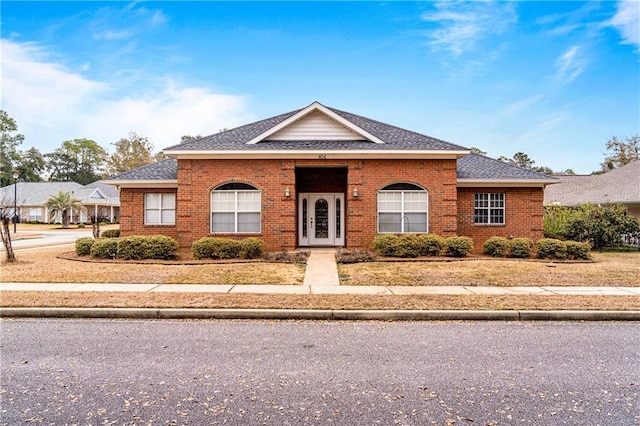 view of front facade with a shingled roof and brick siding