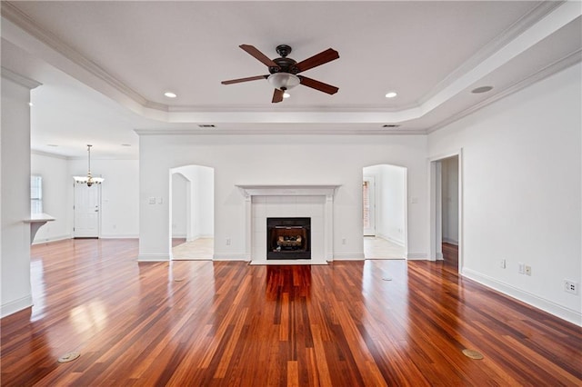 404 Savannah Ln, Foley, AL 36535 - unfurnished living room featuring arched walkways, a raised ceiling, a fireplace, and dark wood finished floors