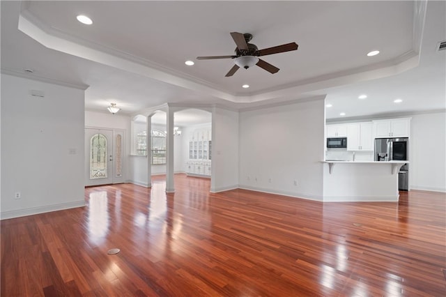 404 Savannah Ln, Foley, AL 36535 - unfurnished living room with a tray ceiling, ceiling fan, ornate columns, and wood finished floors