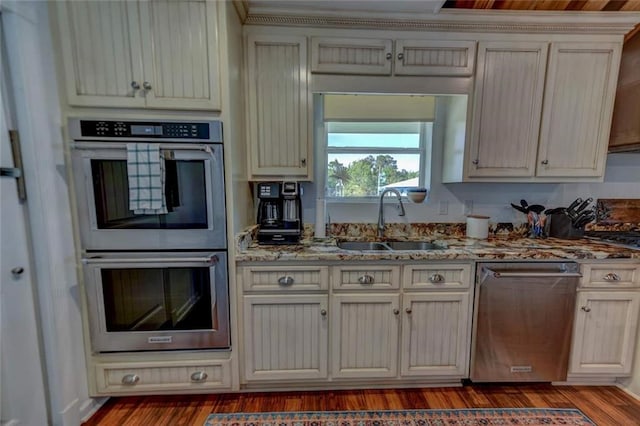 kitchen featuring light stone counters, sink, dark hardwood / wood-style floors, and appliances with stainless steel finishes